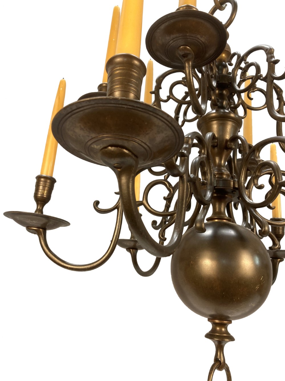 A nineteenth-century multi-tiered bronze chandelier in the Dutch taste featuring scrolling S-curved arms, cylindrical candle nozzles with drip pans, and a central baluster stem terminating in a heavy spherical drop. View VI