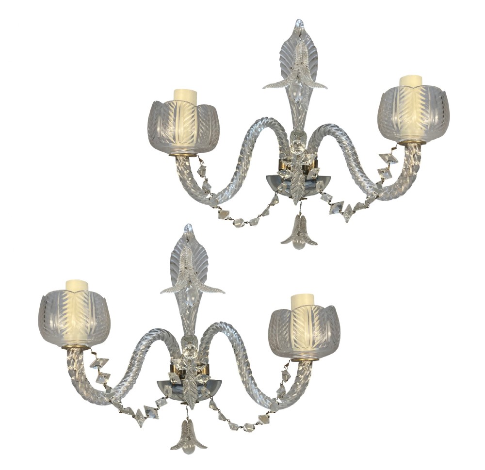 A pair of 1930s Baccarat clear lead crystal twin-branch wall sconces with twisted arms and cut glass candle cups.