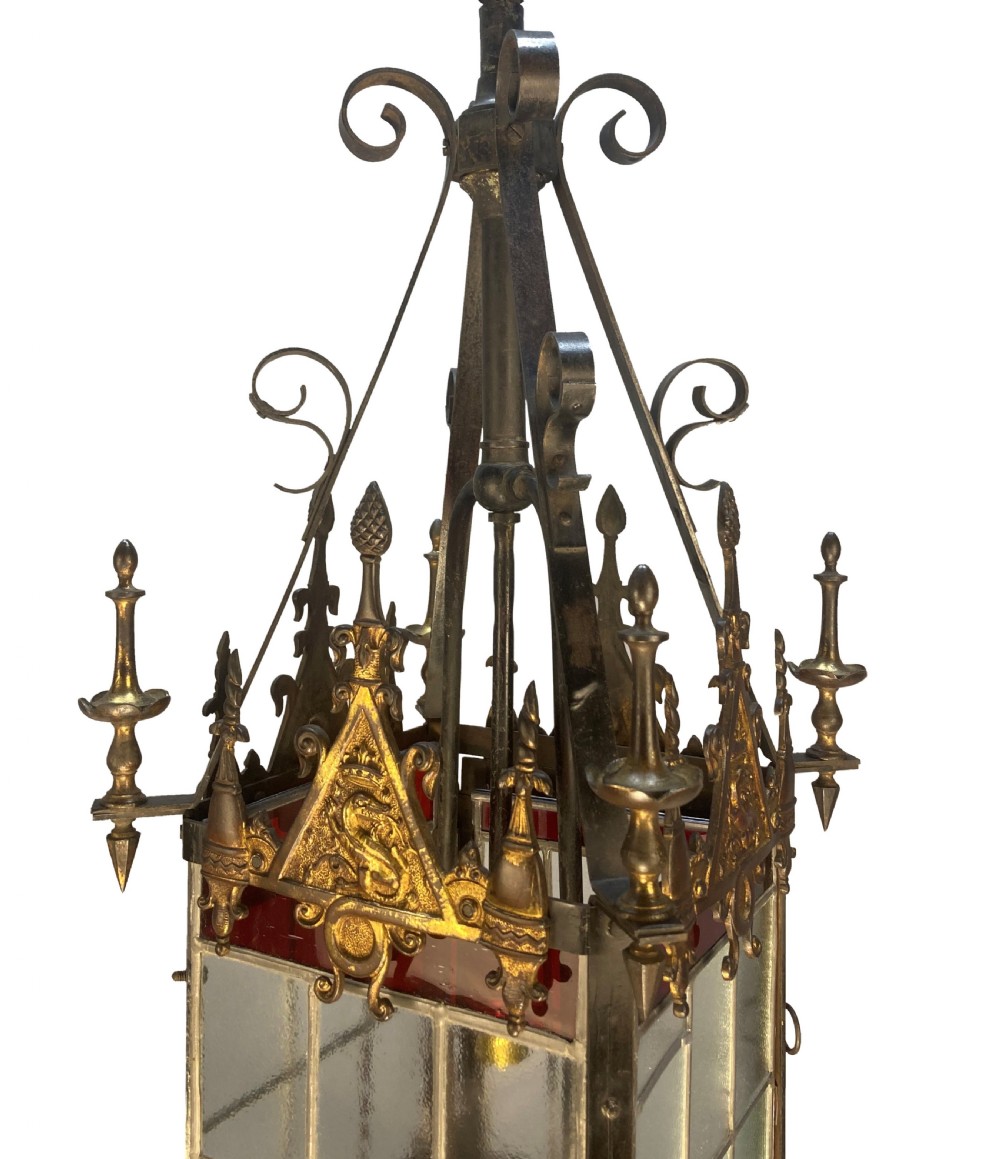 A 19th-century Gothic Revival hanging brass lantern featuring paned glass, ruby red glass borders, ornate crocketed pinnacles, and scrollwork. View V