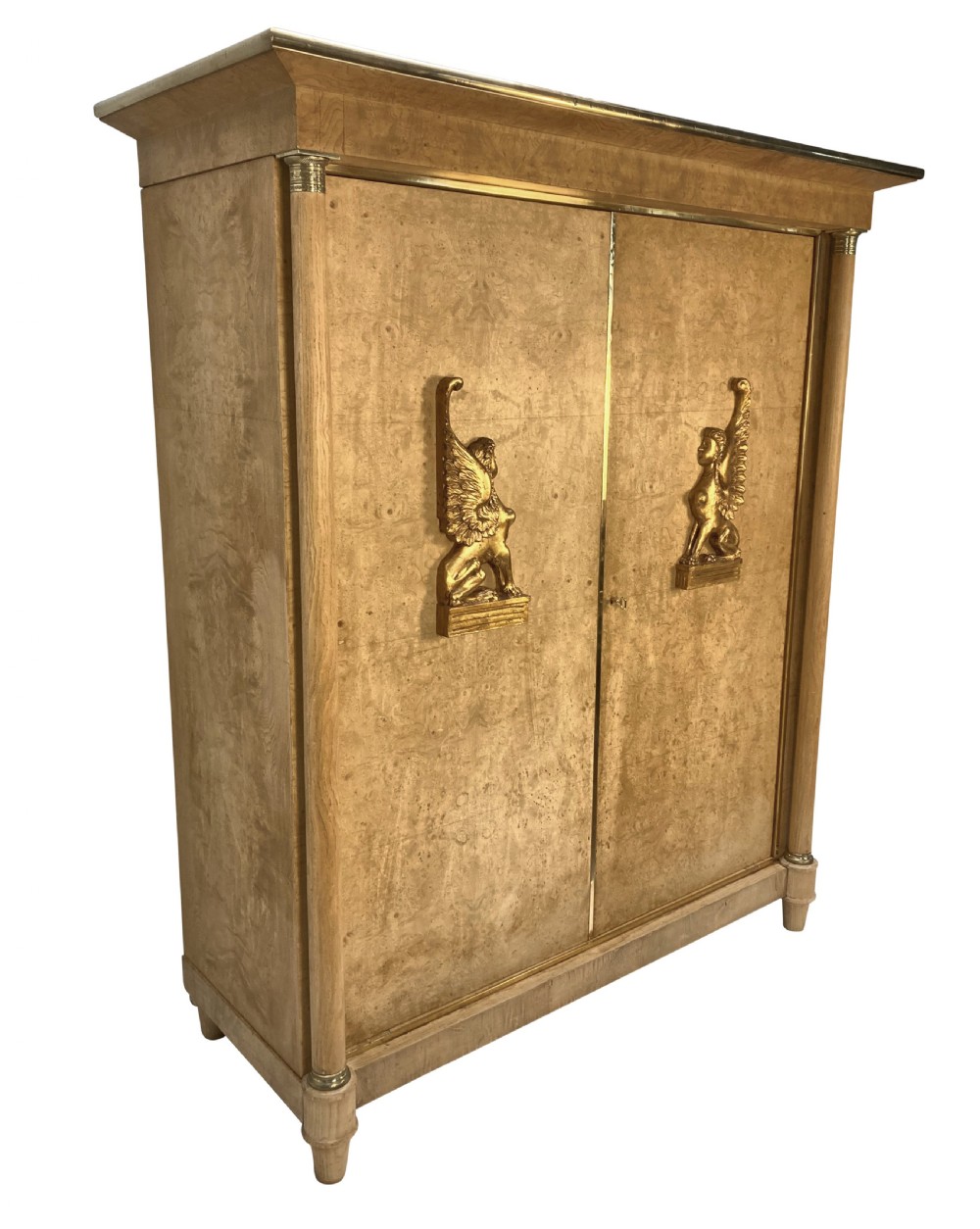 A large two-door Swedish Empire Revival cupboard crafted in light birds eye maple wood featuring gilt winged sphinx mounts and brass trim. View II