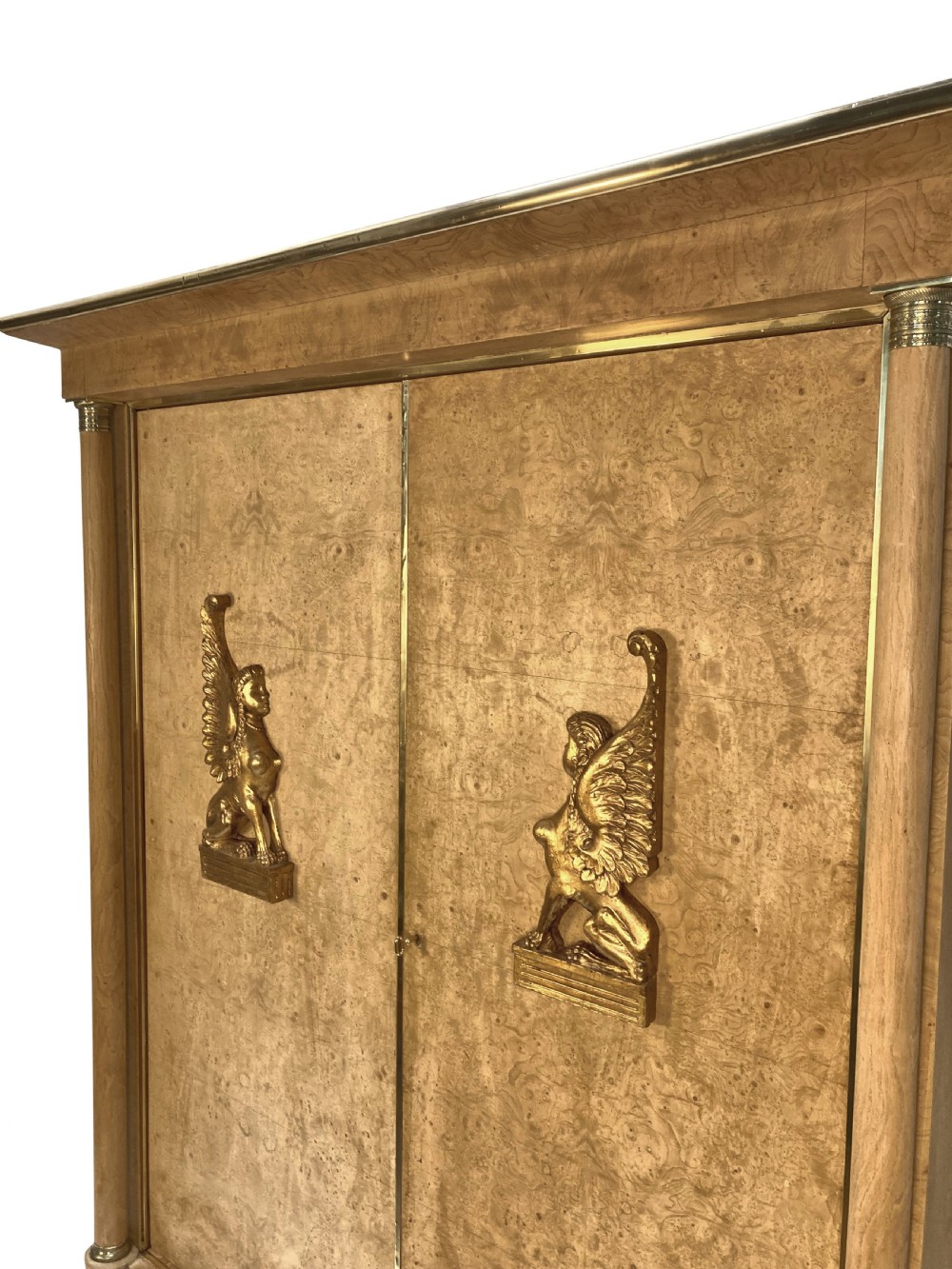 A large two-door Swedish Empire Revival cupboard crafted in light birds eye maple wood featuring gilt winged sphinx mounts and brass trim. View III