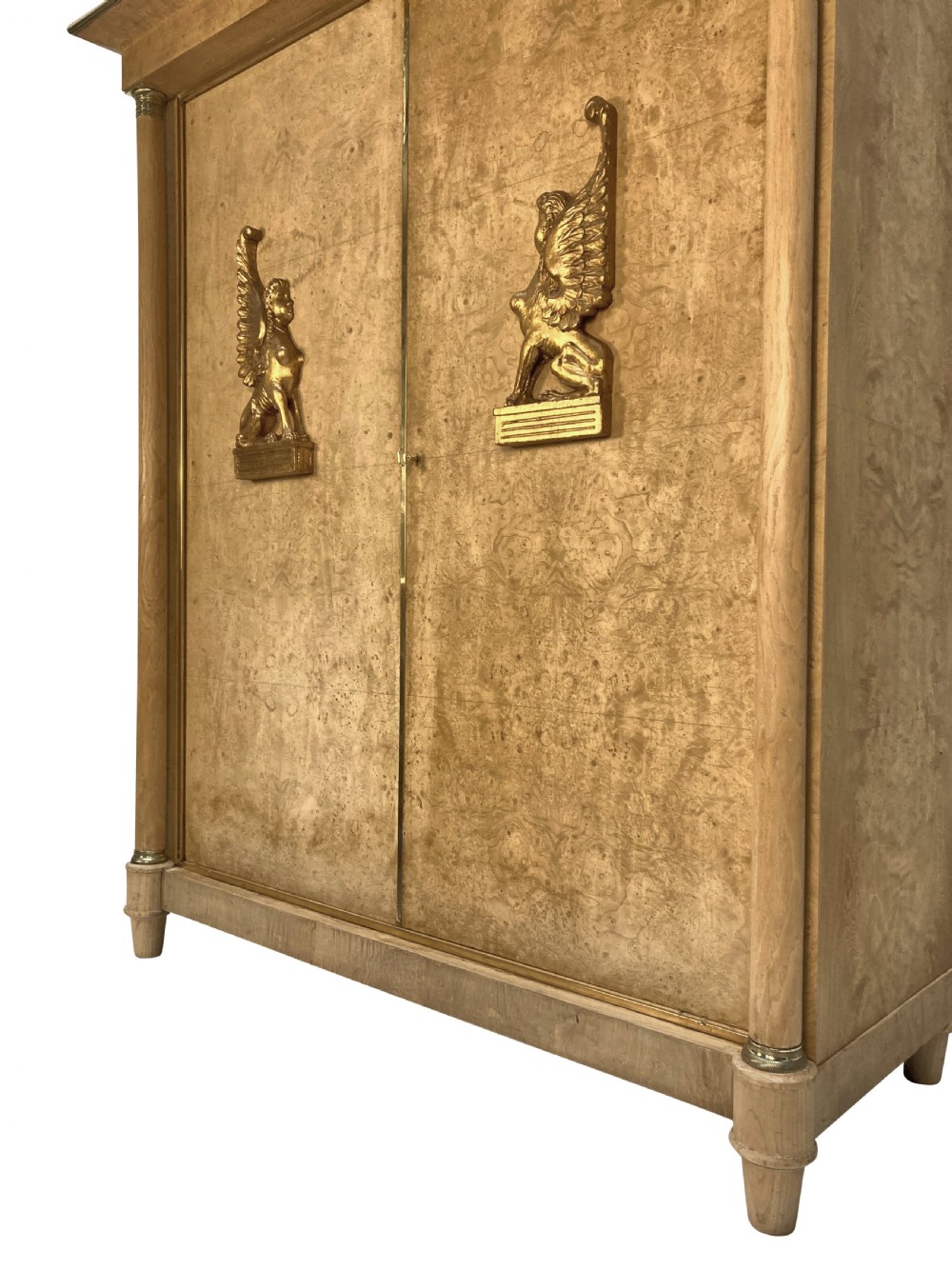 A large two-door Swedish Empire Revival cupboard crafted in light birds eye maple wood featuring gilt winged sphinx mounts and brass trim. View IV