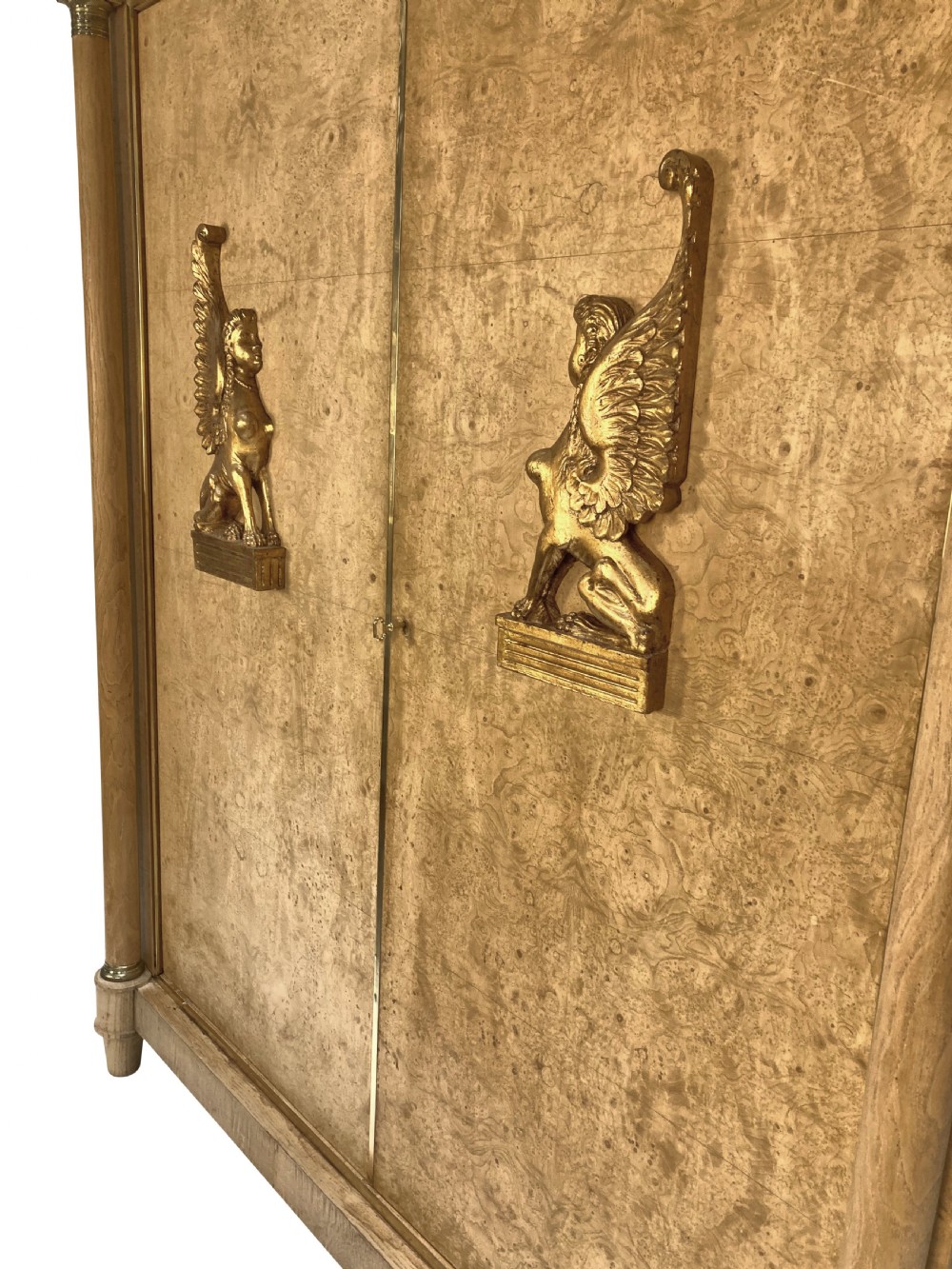 A large two-door Swedish Empire Revival cupboard crafted in light birds eye maple wood featuring gilt winged sphinx mounts and brass trim. View VII