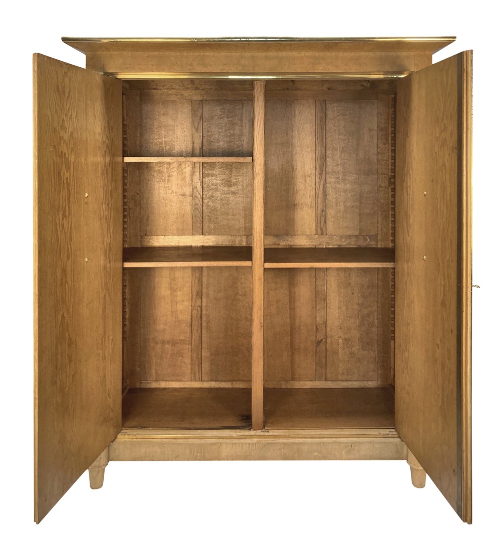 A large two-door Swedish Empire Revival cupboard crafted in light birds eye maple wood featuring gilt winged sphinx mounts and brass trim. View VIII