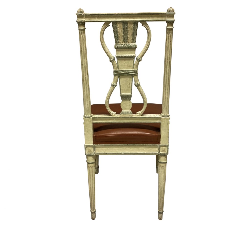 A set of six Louis XVI style cream painted side chairs featuring open carved backs with urn motifs and brown leather upholstered seats with stud detailing. View V
