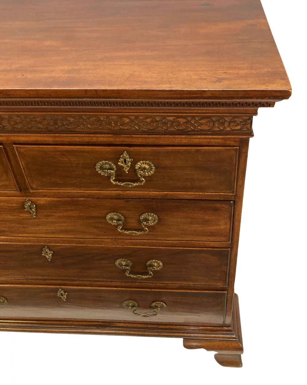 An English Chippendale style mahogany chest of drawers featuring ornate brass handles, a carved fretwork frieze, and bracket feet. View III