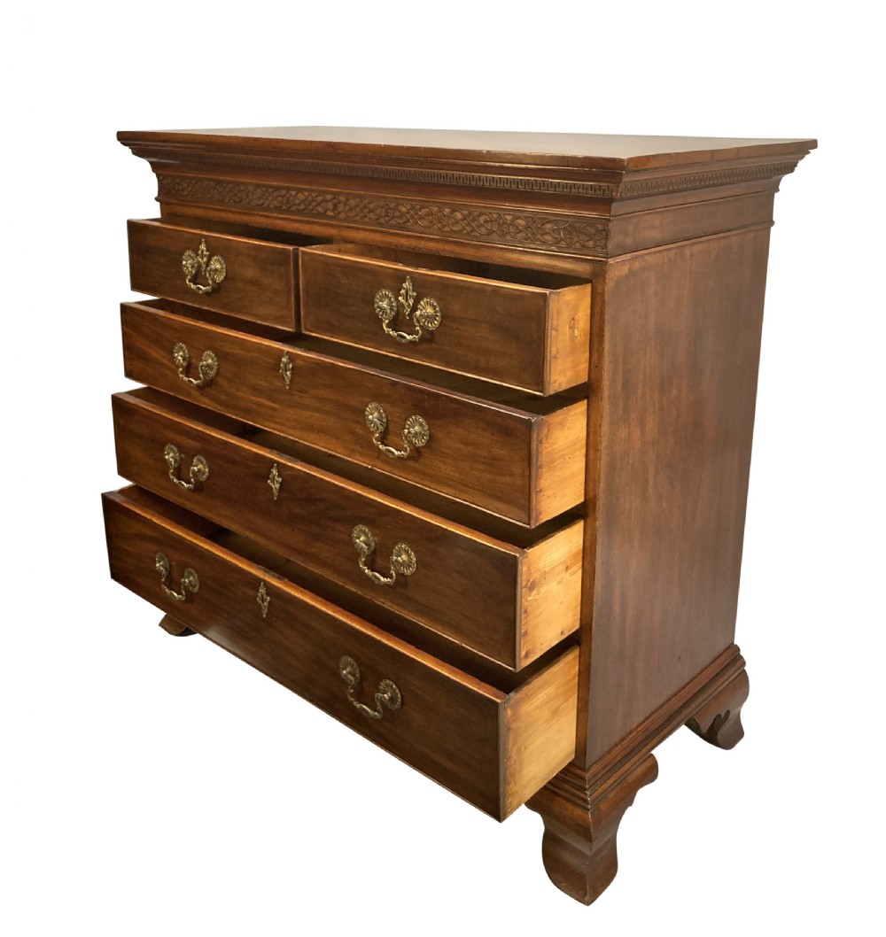 An English Chippendale style mahogany chest of drawers featuring ornate brass handles, a carved fretwork frieze, and bracket feet. View V