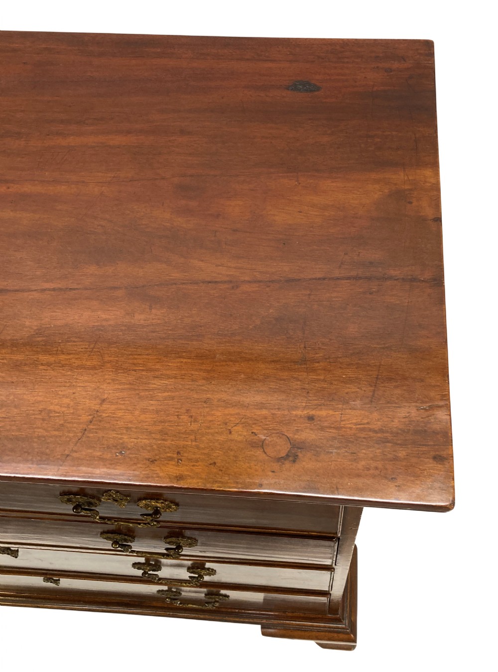 An English Chippendale style mahogany chest of drawers featuring ornate brass handles, a carved fretwork frieze, and bracket feet. View VII