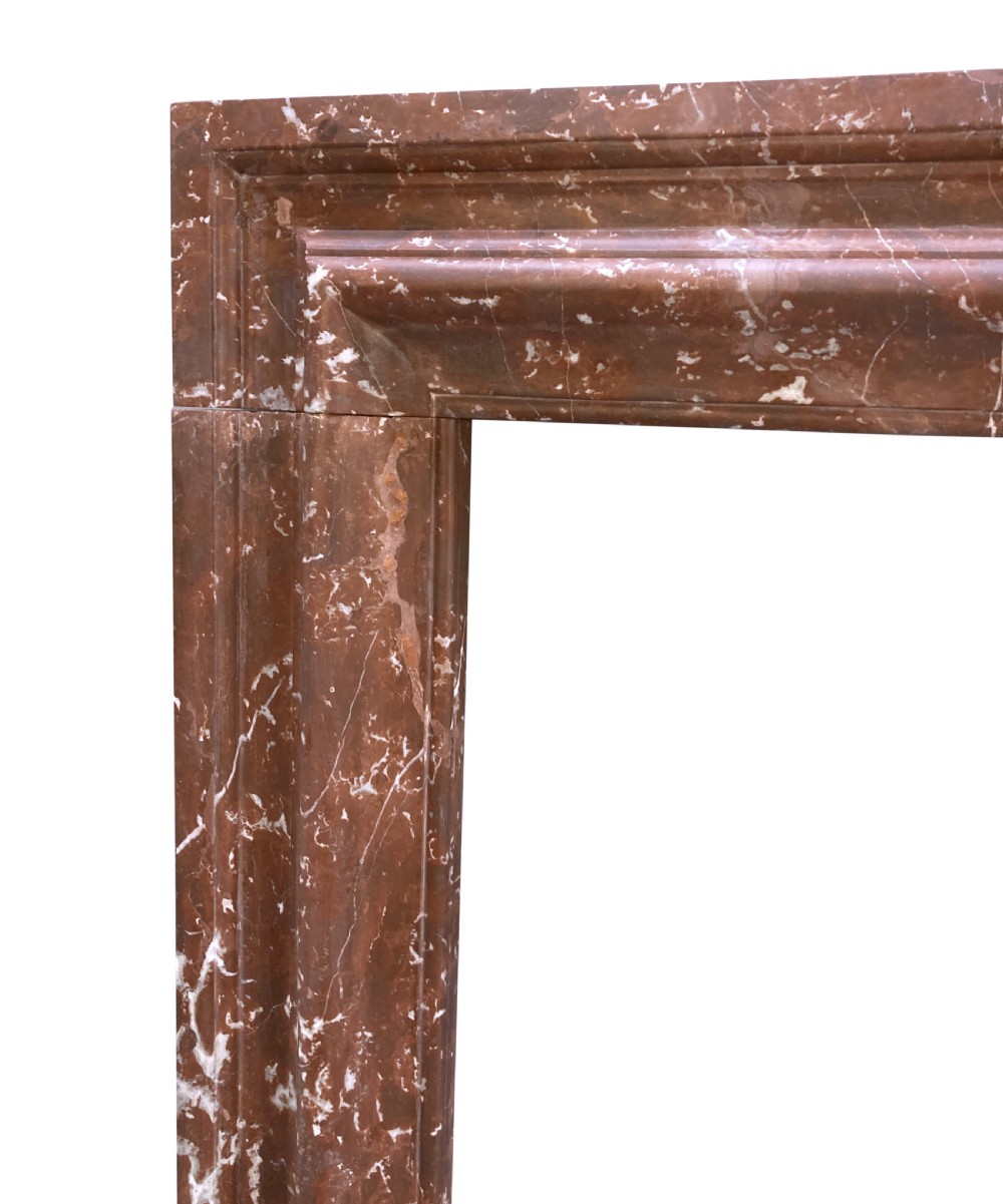 A red and white veined marble fire surround with a convex bolection moulding profile and block plinth bases. View III