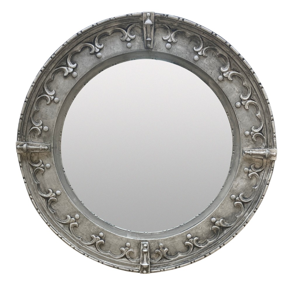 A circular wall mirror featuring a carved oak frame finished in grey gesso with Gothic revival scrolling strapwork and raised cardinal accents.