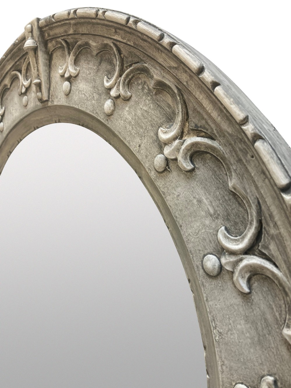 A circular wall mirror featuring a carved oak frame finished in grey gesso with Gothic revival scrolling strapwork and raised cardinal accents. View III