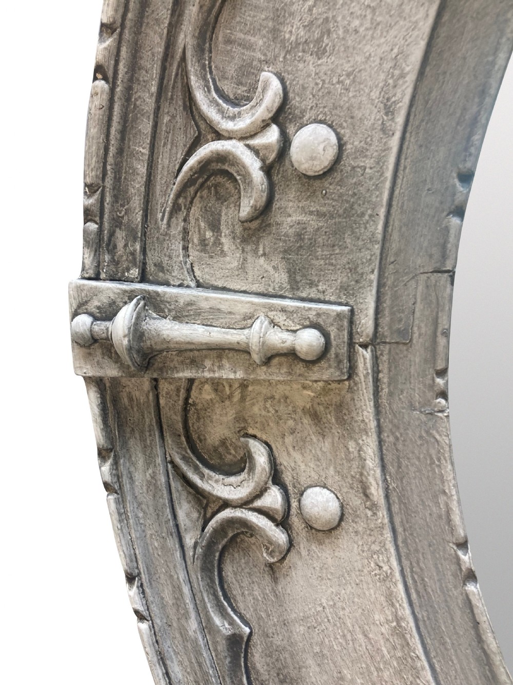 A circular wall mirror featuring a carved oak frame finished in grey gesso with Gothic revival scrolling strapwork and raised cardinal accents. View IV