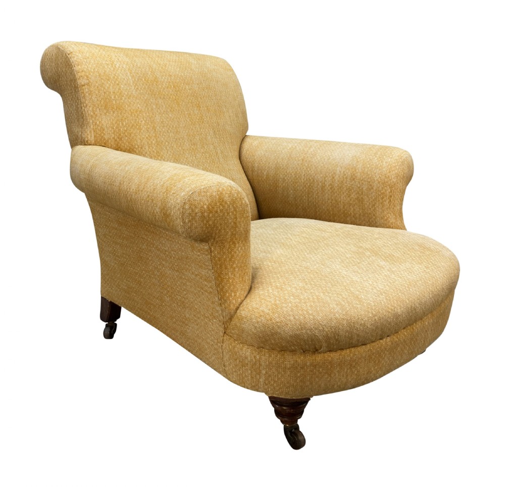 A low-slung Howard style club armchair upholstered in yellow textured fabric with turned wood front legs on castors.