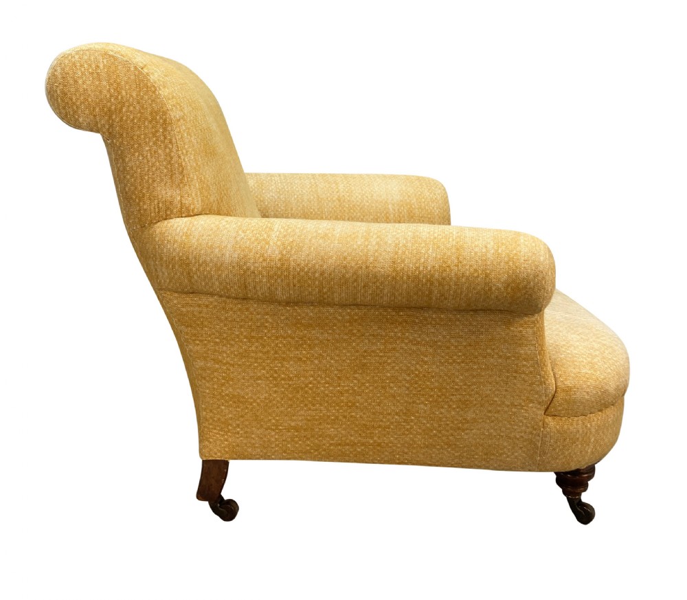 A low-slung Howard style club armchair upholstered in yellow textured fabric with turned wood front legs on castors. View III