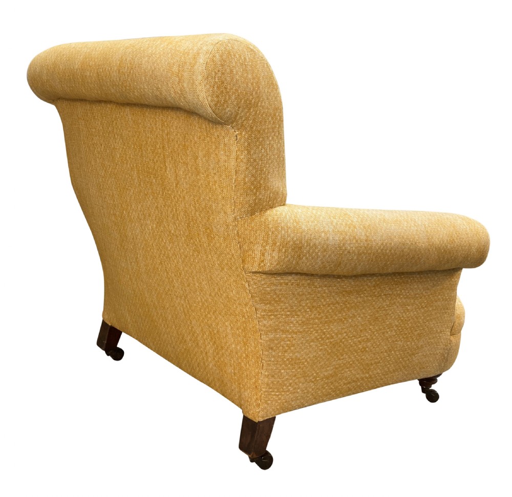 A low-slung Howard style club armchair upholstered in yellow textured fabric with turned wood front legs on castors. View IV