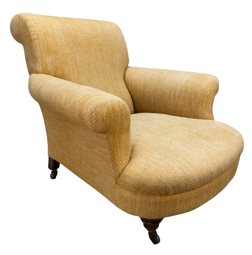 A low-slung Howard style club armchair upholstered in yellow textured fabric with turned wood front legs on castors. View V