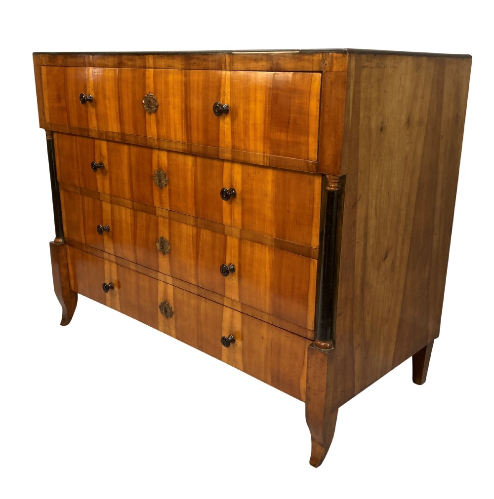 An early nineteenth-century Biedermeier chest of four drawers crafted from figured timber veneer, flanked by ebonised side columns and supported by tapered front legs. View II