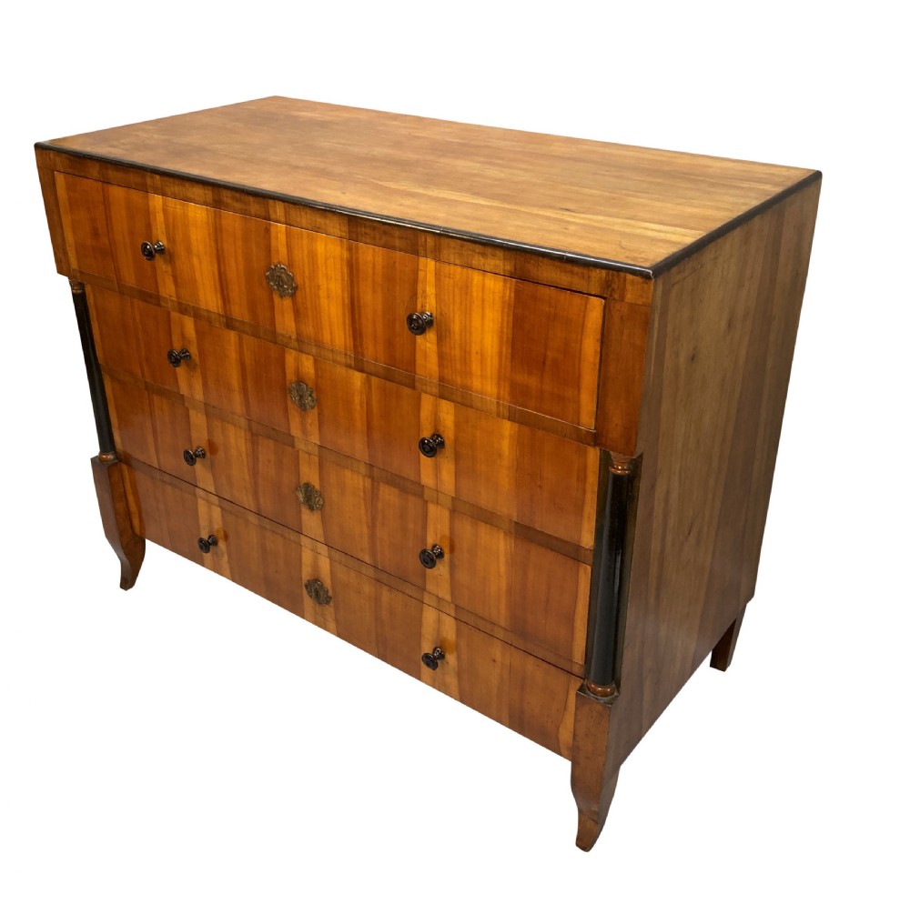 An early nineteenth-century Biedermeier chest of four drawers crafted from figured timber veneer, flanked by ebonised side columns and supported by tapered front legs. View III