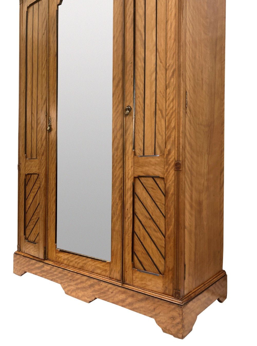 An Aesthetic Movement satin birch wardrobe featuring a central mirrored door flanked by geometric panelled side doors and a carved frieze. View VI