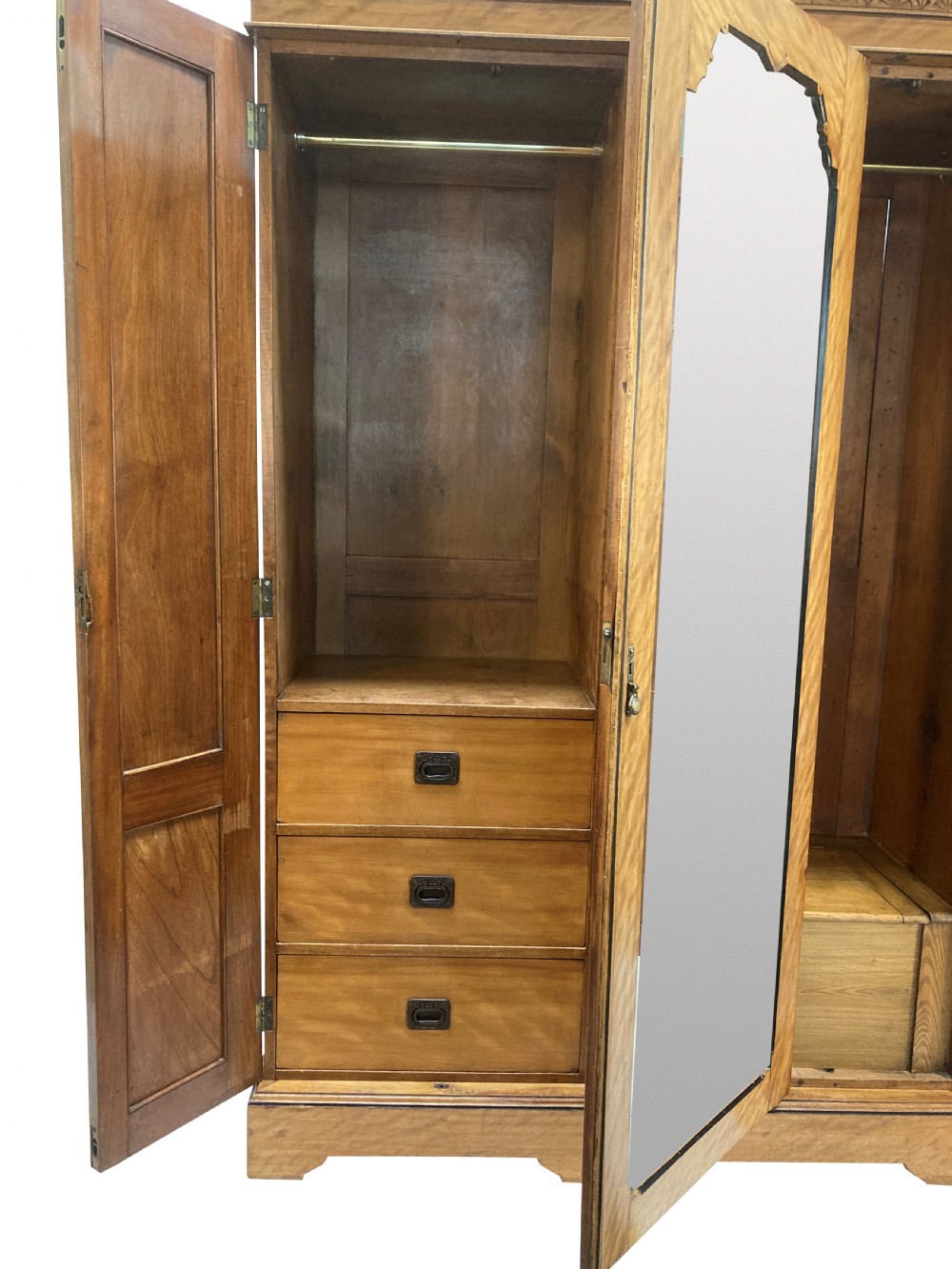 An Aesthetic Movement satin birch wardrobe featuring a central mirrored door flanked by geometric panelled side doors and a carved frieze. View VII