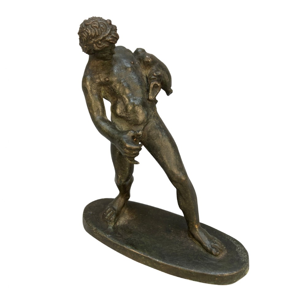 A dark patinated bronze statuette depicting the mythological figure Dionysus standing on an oval base.