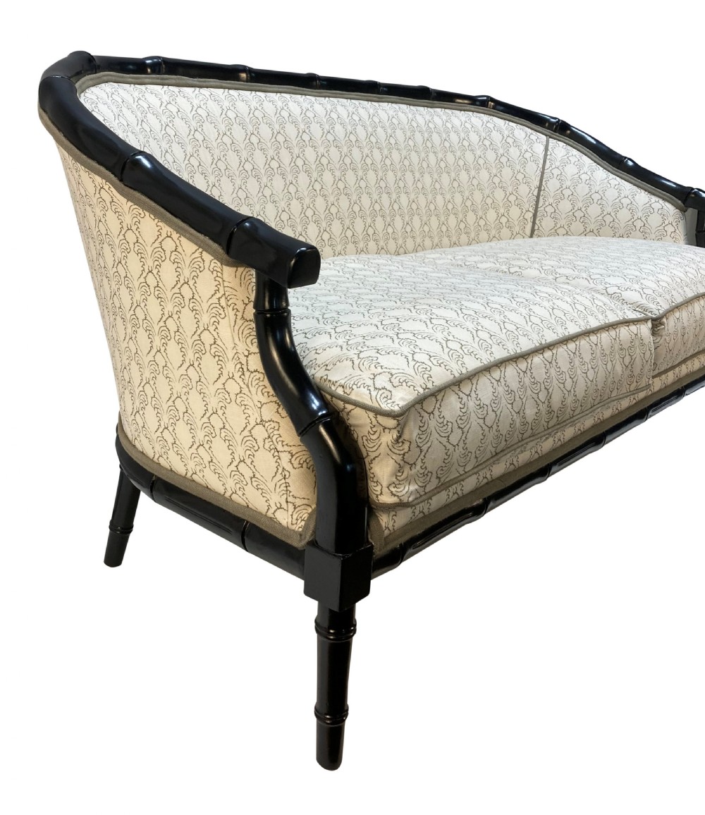 A 1930s French faux bamboo sofa featuring a black lacquered carved frame with a curved back and cream patterned upholstery. View II
