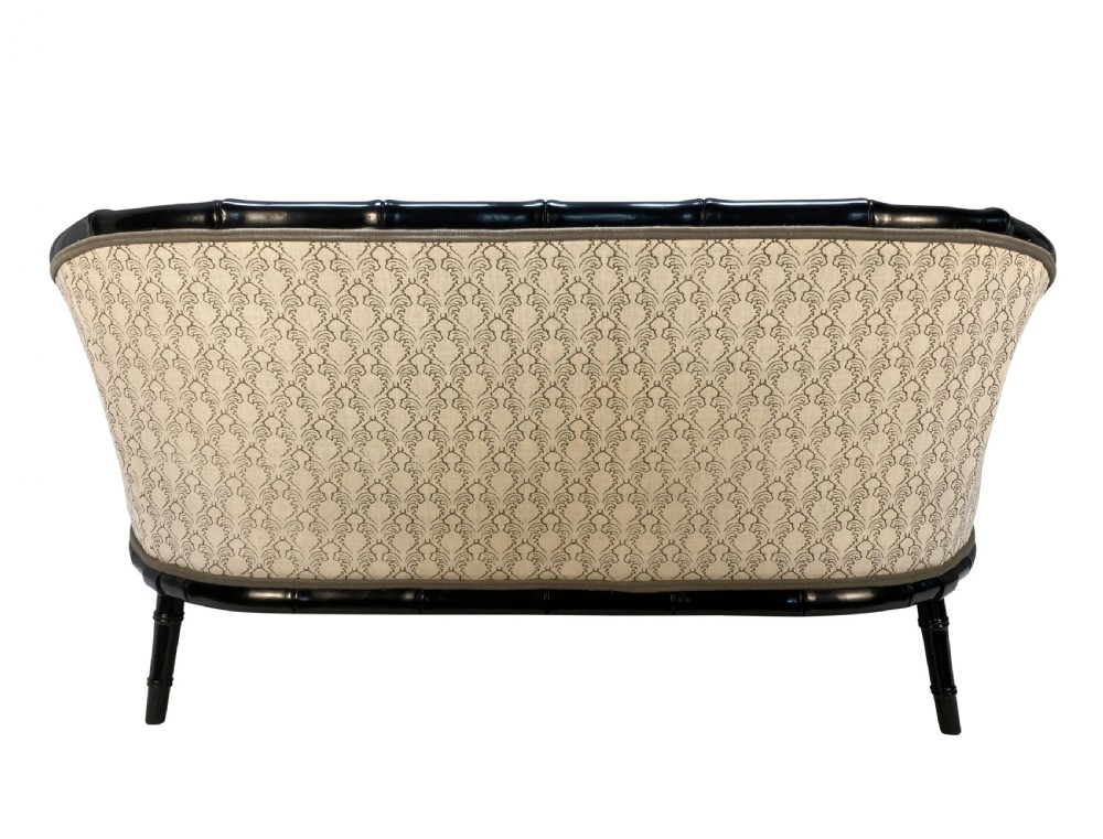 A 1930s French faux bamboo sofa featuring a black lacquered carved frame with a curved back and cream patterned upholstery. View V