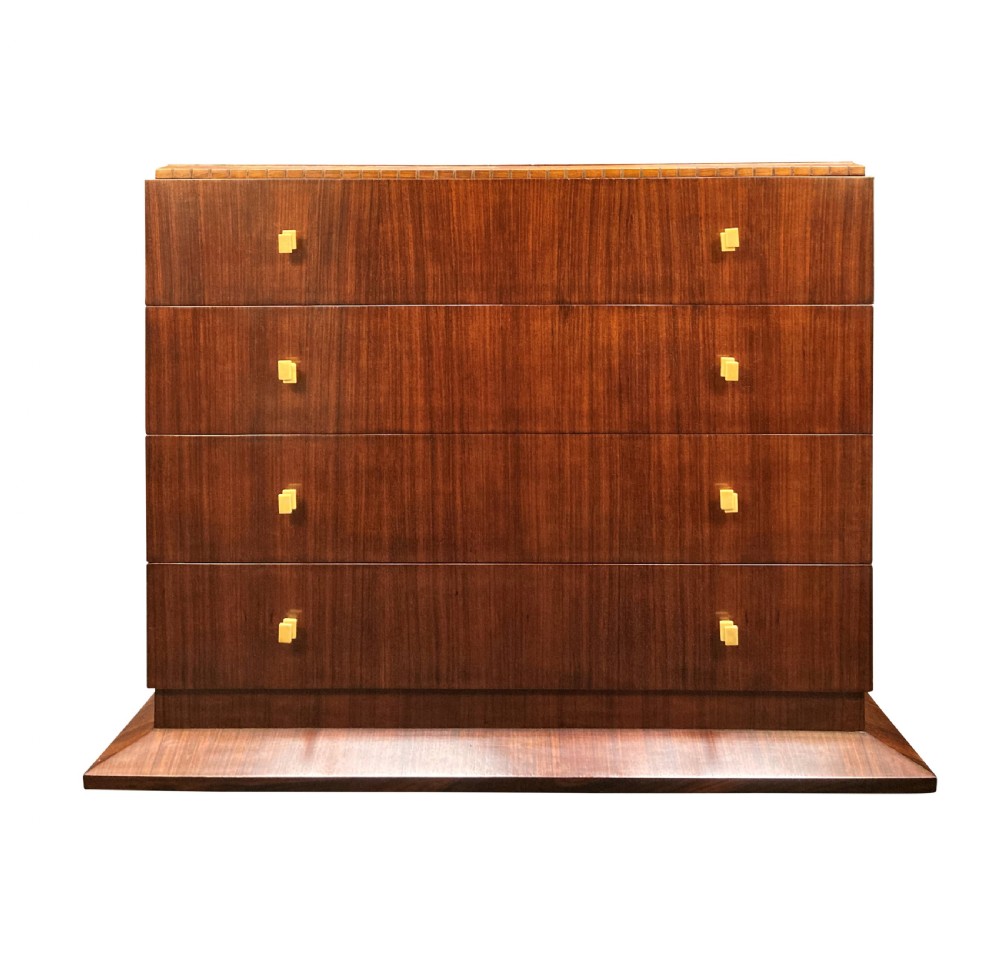An Art Deco dark wood commode featuring four stacked drawers with cream-coloured Bakelite handles resting on a stepped plinth base.
