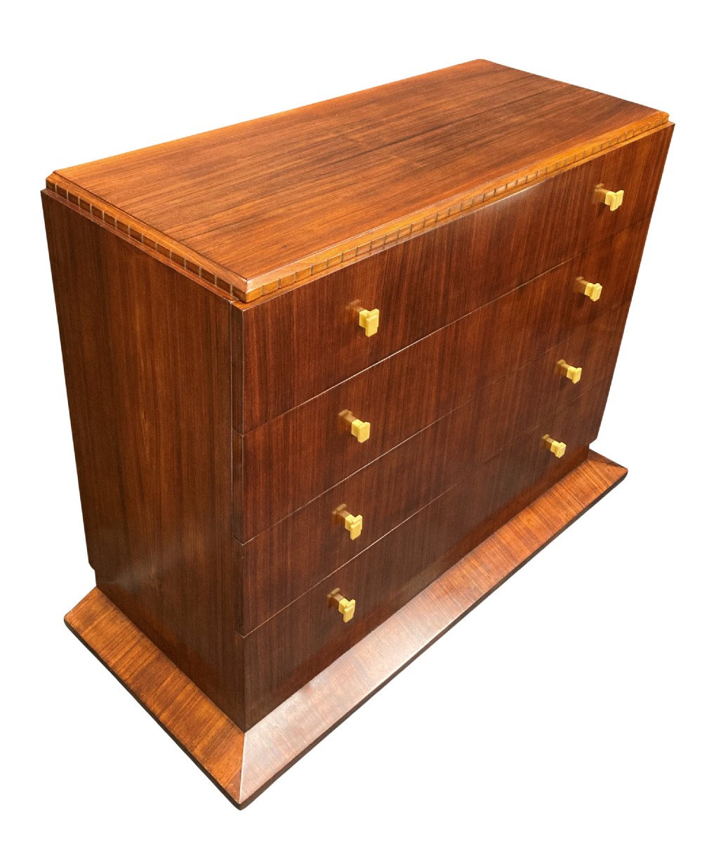 An Art Deco dark wood commode featuring four stacked drawers with cream-coloured Bakelite handles resting on a stepped plinth base. View V