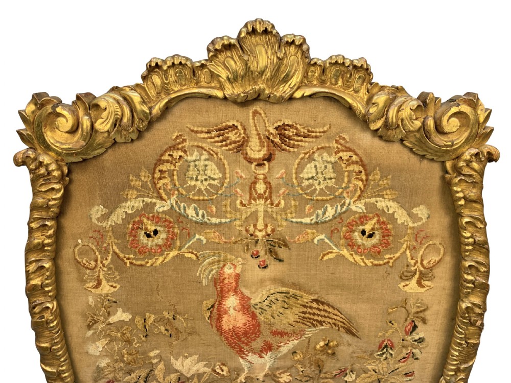 A George III giltwood fire screen with a carved gold frame and a central needlepoint panel depicting a bird and floral motifs. View II