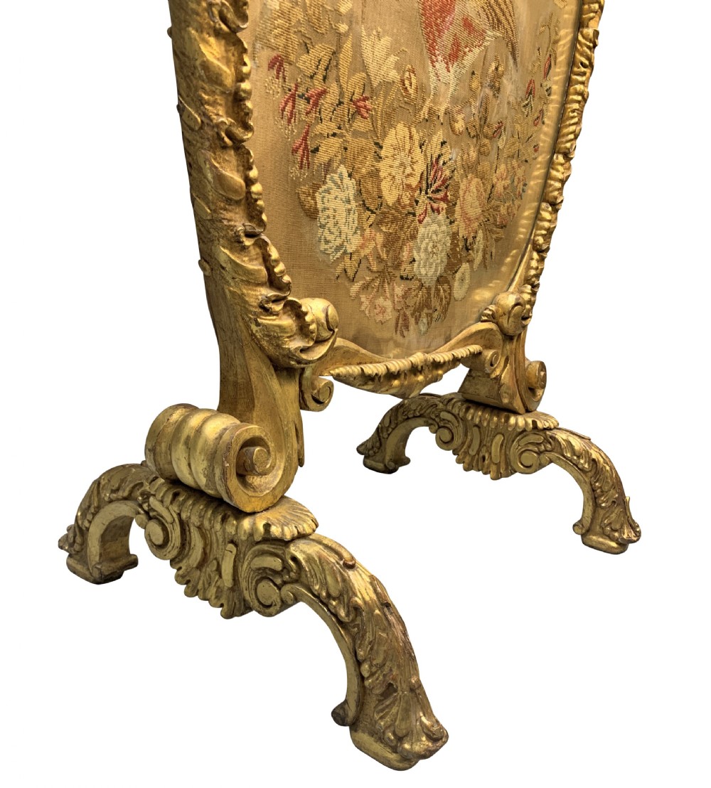 A George III giltwood fire screen with a carved gold frame and a central needlepoint panel depicting a bird and floral motifs. View IV