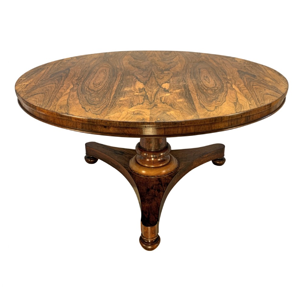 A circular William IV rosewood tilt-top centre table featuring a book-matched veneer top, turned column, and triform base on bun feet.