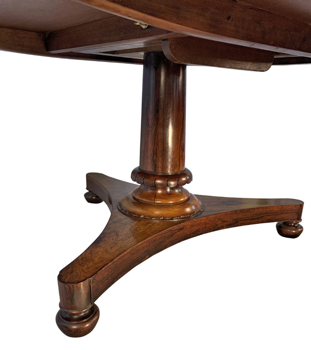A circular William IV rosewood tilt-top centre table featuring a book-matched veneer top, turned column, and triform base on bun feet. View IV