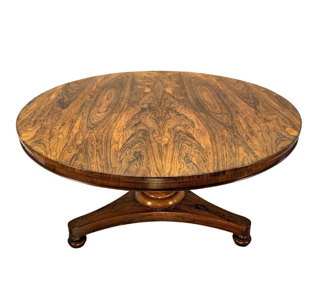A circular William IV rosewood tilt-top centre table featuring a book-matched veneer top, turned column, and triform base on bun feet. View V