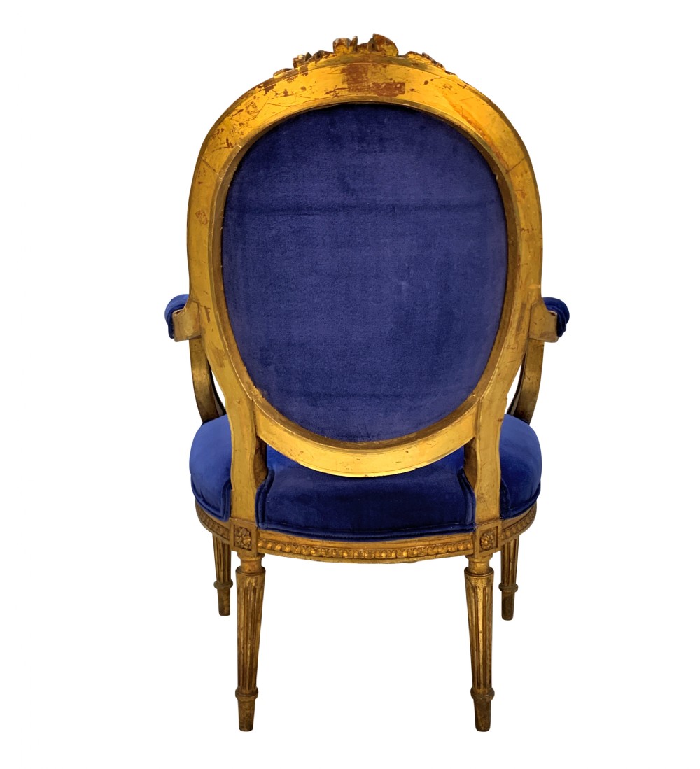 A set of four Louis XVI style armchairs featuring carved giltwood frames with oval medallion backs and royal blue velvet upholstery. View V