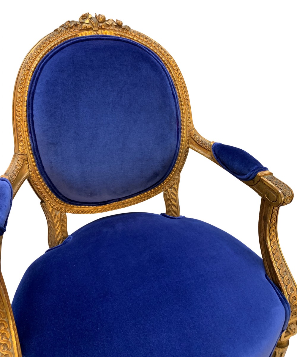 A set of four Louis XVI style armchairs featuring carved giltwood frames with oval medallion backs and royal blue velvet upholstery. View VI