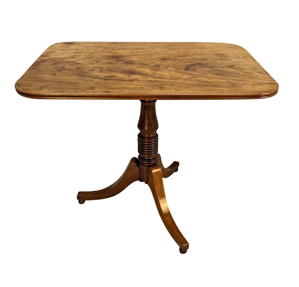 A George III mahogany side table featuring a rounded rectangular tilt-top on a turned pedestal with three splayed tripod legs.