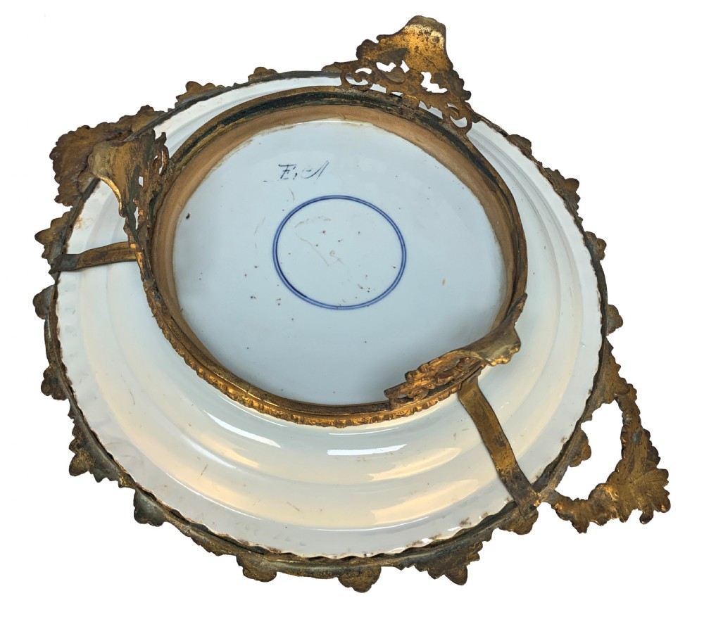 A circular Chinese Imari porcelain plate decorated with blue and red floral patterns, set within a gilt bronze ormolu frame with foliage handles. View IV