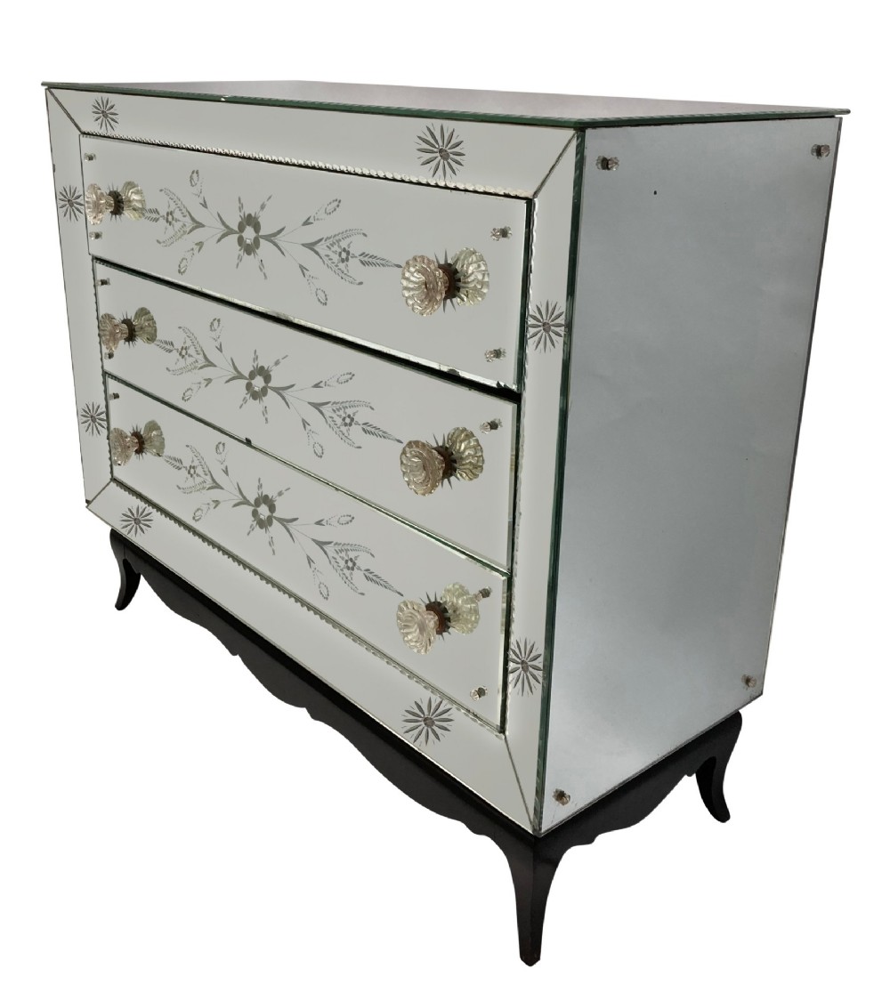 A 1930s French Art Deco three-drawer chest clad entirely in etched mirrored glass with starburst corner motifs and a black wooden base. View II