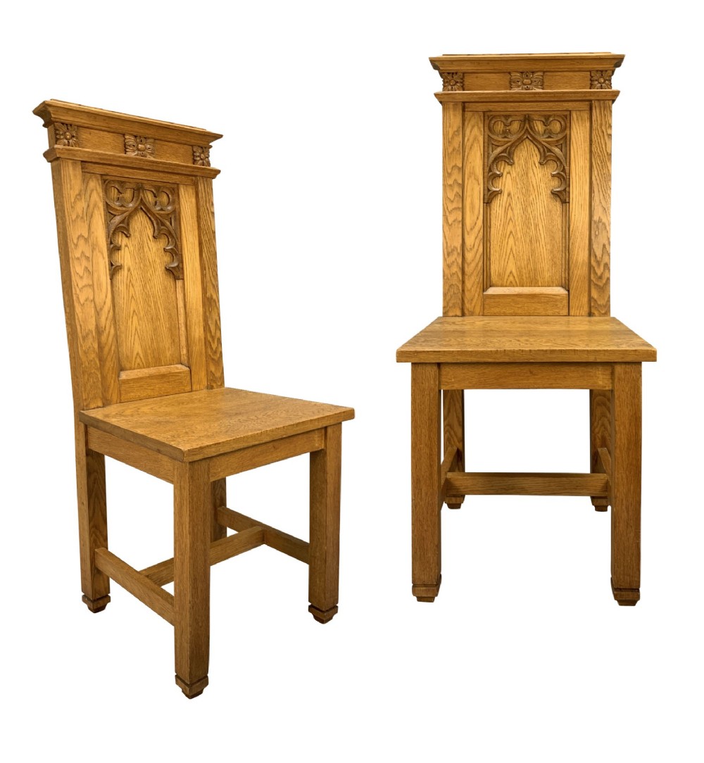 A set of four solid English oak hall chairs featuring carved Gothic arch panels on the backrests, flat solid seats, and straight legs with H-stretchers. View II