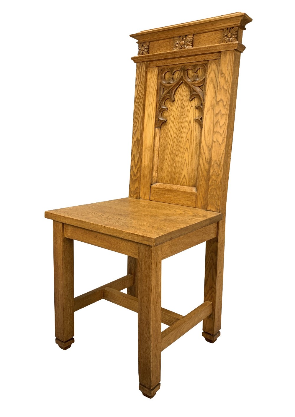 A set of four solid English oak hall chairs featuring carved Gothic arch panels on the backrests, flat solid seats, and straight legs with H-stretchers. View IV