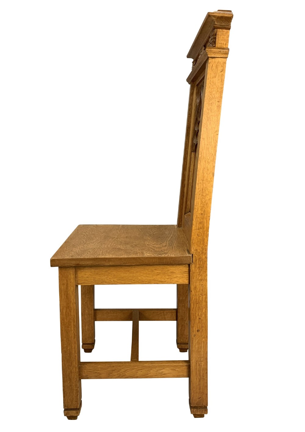 A set of four solid English oak hall chairs featuring carved Gothic arch panels on the backrests, flat solid seats, and straight legs with H-stretchers. View V