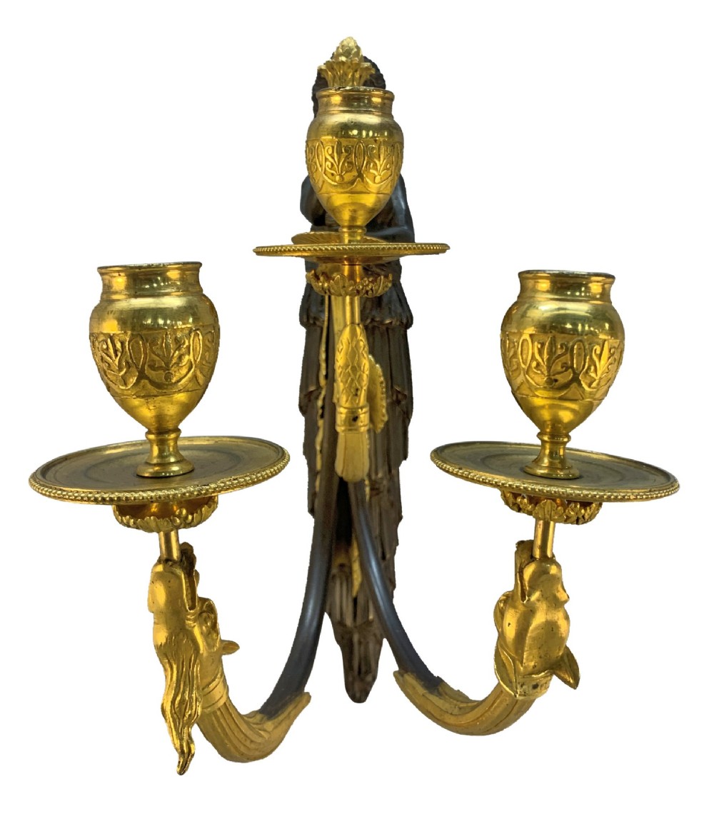 A pair of Neoclassical wall lights featuring dark patinated bronze female caryatid figures holding gilt bronze multi-arm candle holders with urn nozzles. View V