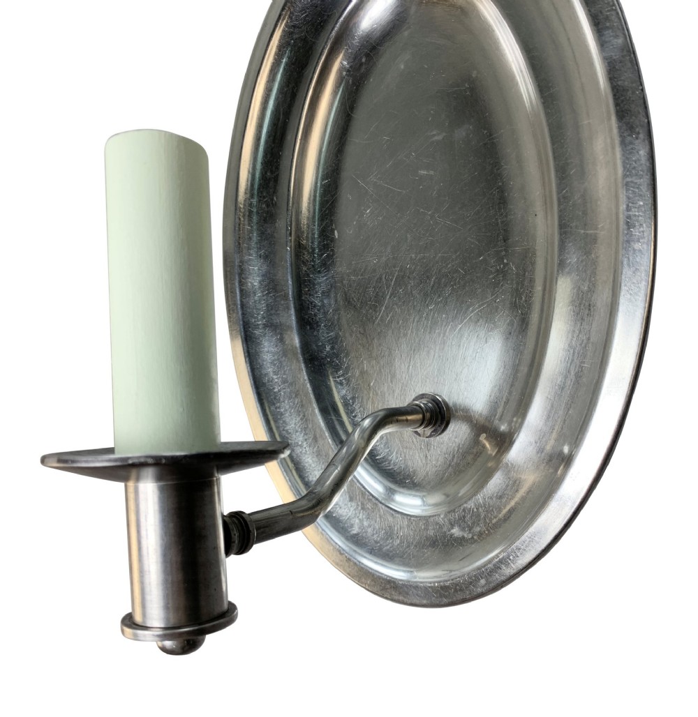 A set of six oval silver-plated single-arm wall sconces featuring reflective backplates and candle-style light sockets. View V