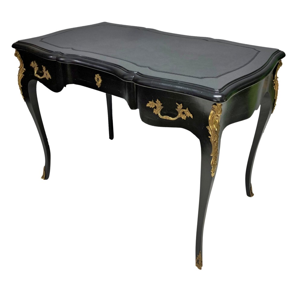 A black lacquered Louis XV style writing table featuring a serpentine top with a leather writing surface, decorative gilt bronze mounts, three frieze drawers, and cabriole legs with gilded sabots. View II