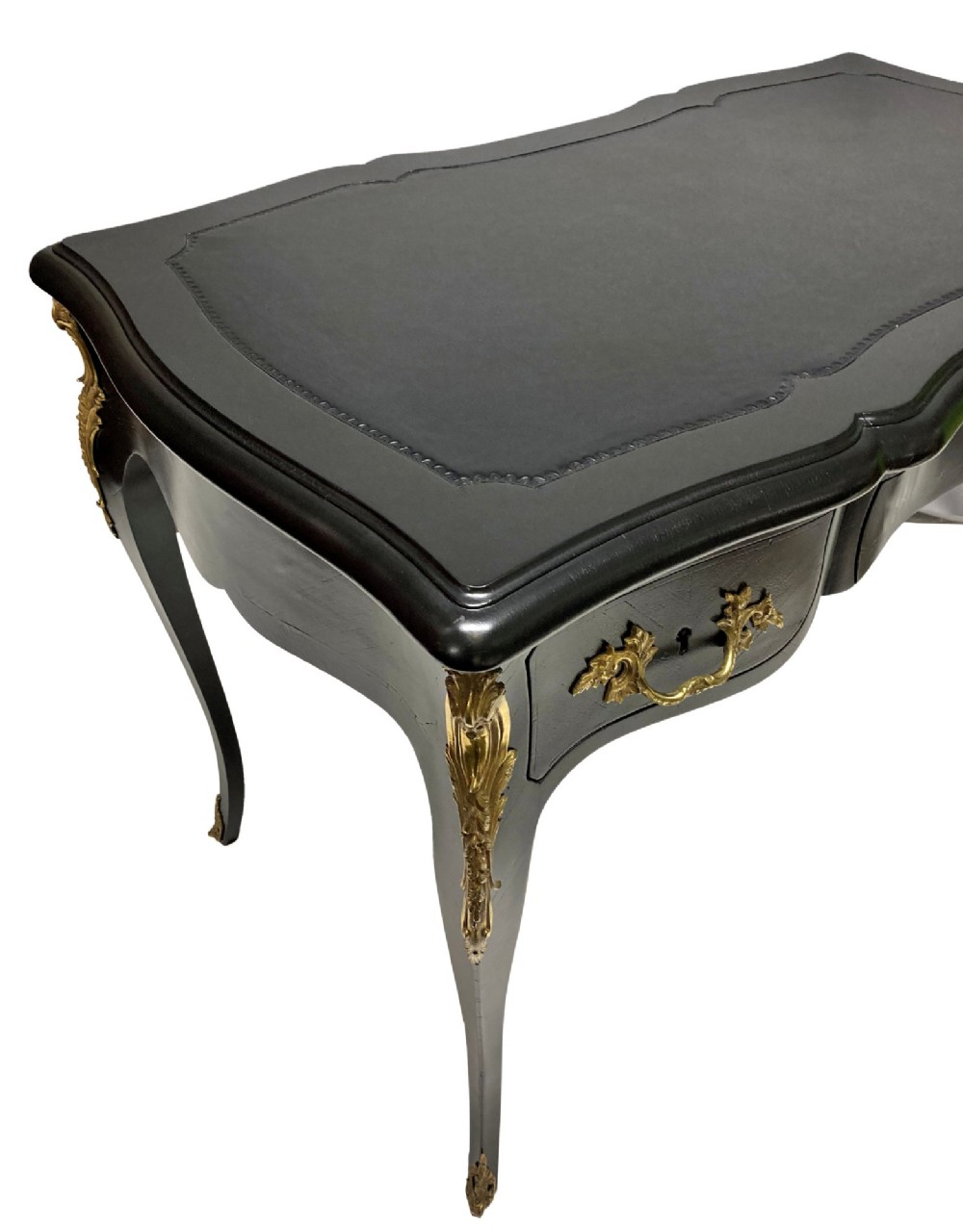 A black lacquered Louis XV style writing table featuring a serpentine top with a leather writing surface, decorative gilt bronze mounts, three frieze drawers, and cabriole legs with gilded sabots. View III