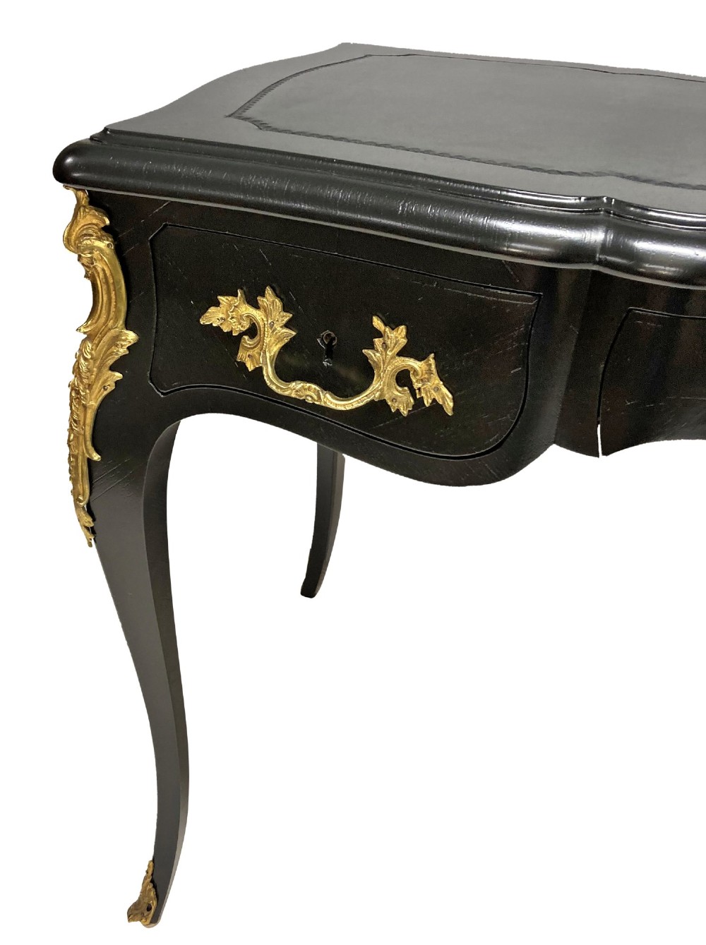 A black lacquered Louis XV style writing table featuring a serpentine top with a leather writing surface, decorative gilt bronze mounts, three frieze drawers, and cabriole legs with gilded sabots. View IV