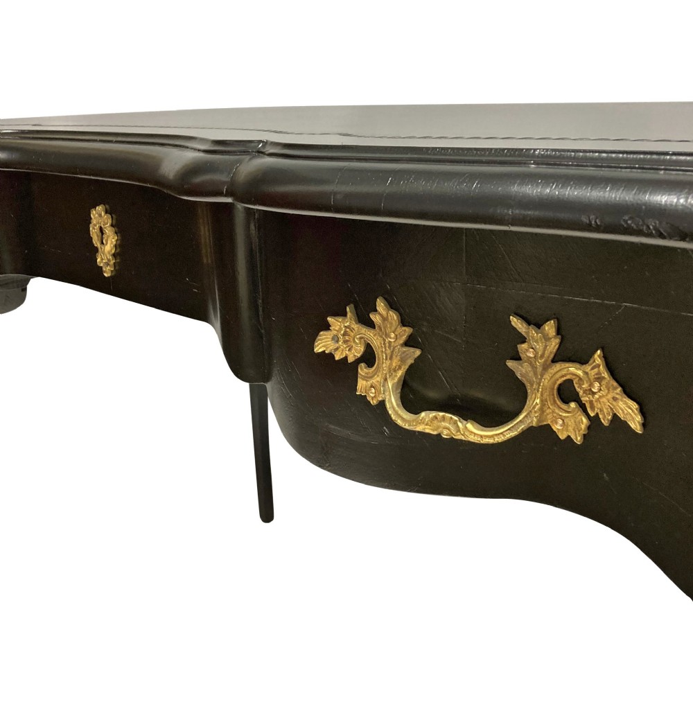 A black lacquered Louis XV style writing table featuring a serpentine top with a leather writing surface, decorative gilt bronze mounts, three frieze drawers, and cabriole legs with gilded sabots. View V