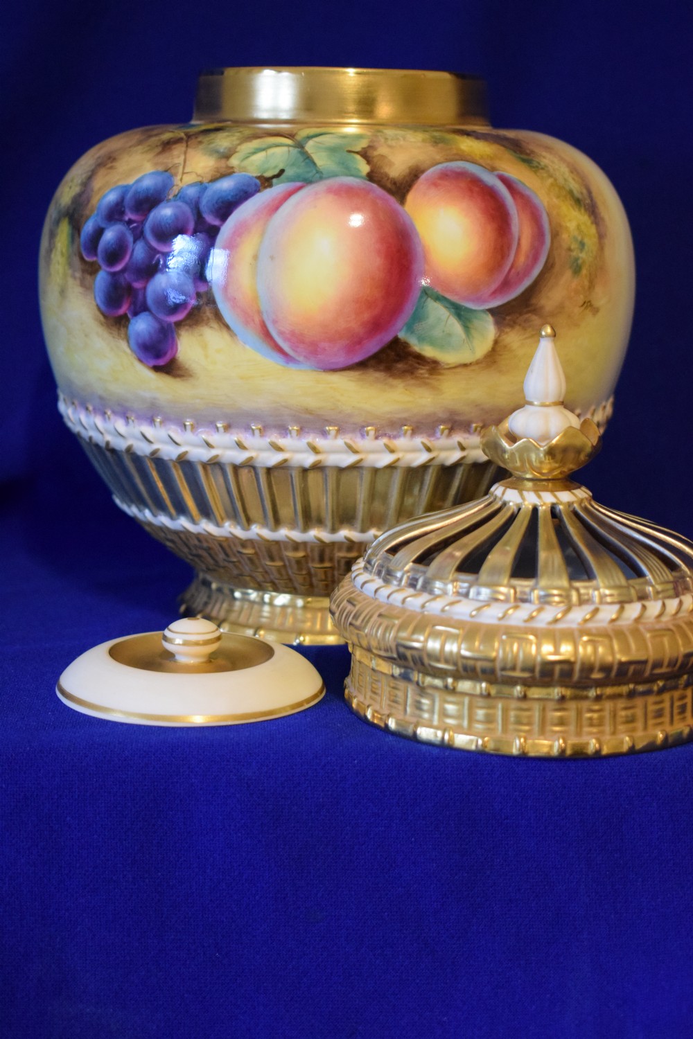 A Royal Worcester three-piece porcelain potpourri vase featuring hand-painted fruit artwork, gilded basketweave lower trim, and a reticulated gold cover. View III