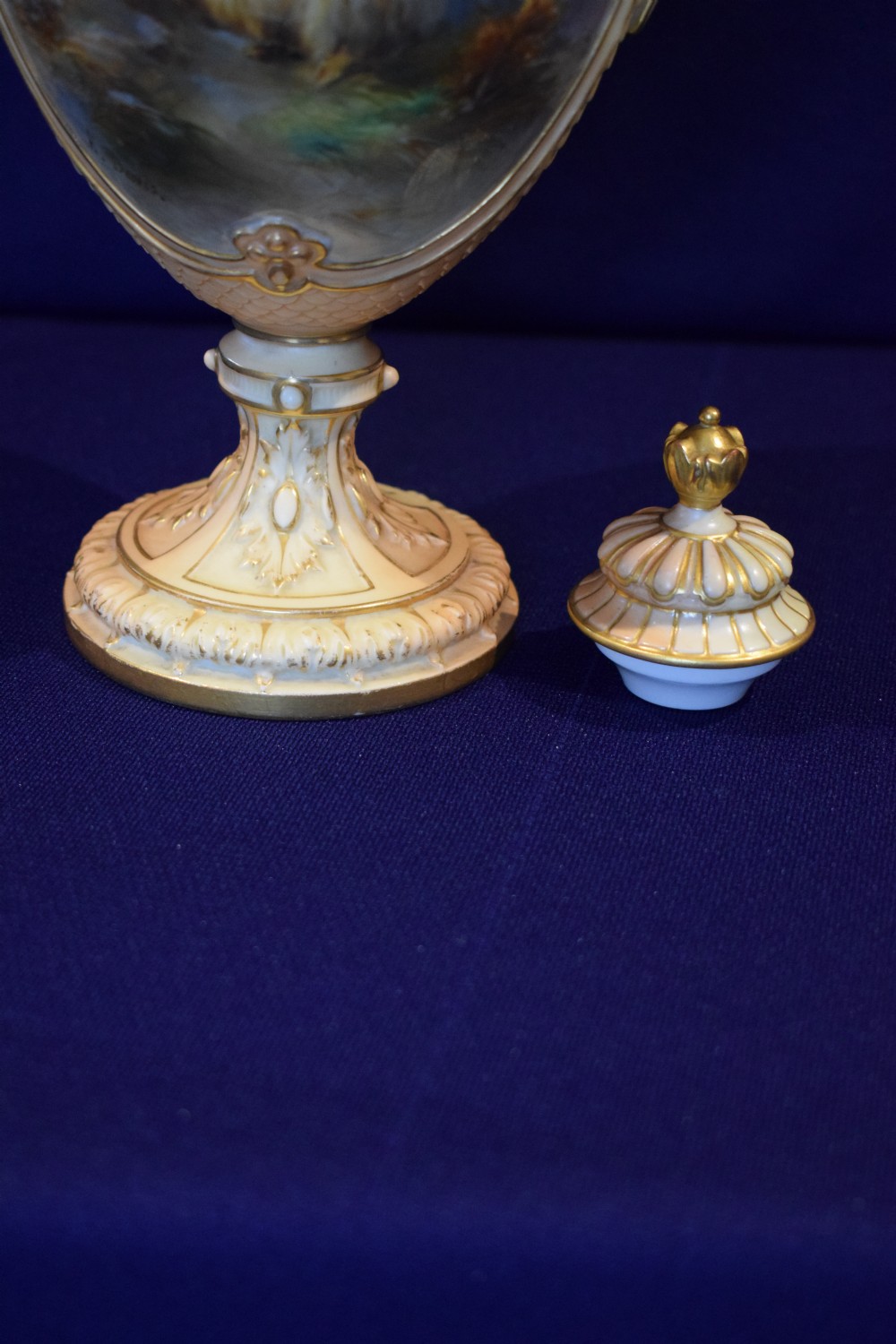 A tall blush ivory porcelain urn featuring two beast-head handles, a detailed hand-painted panel of sheep in a highland landscape, and heavy gilded rims and base. View IV